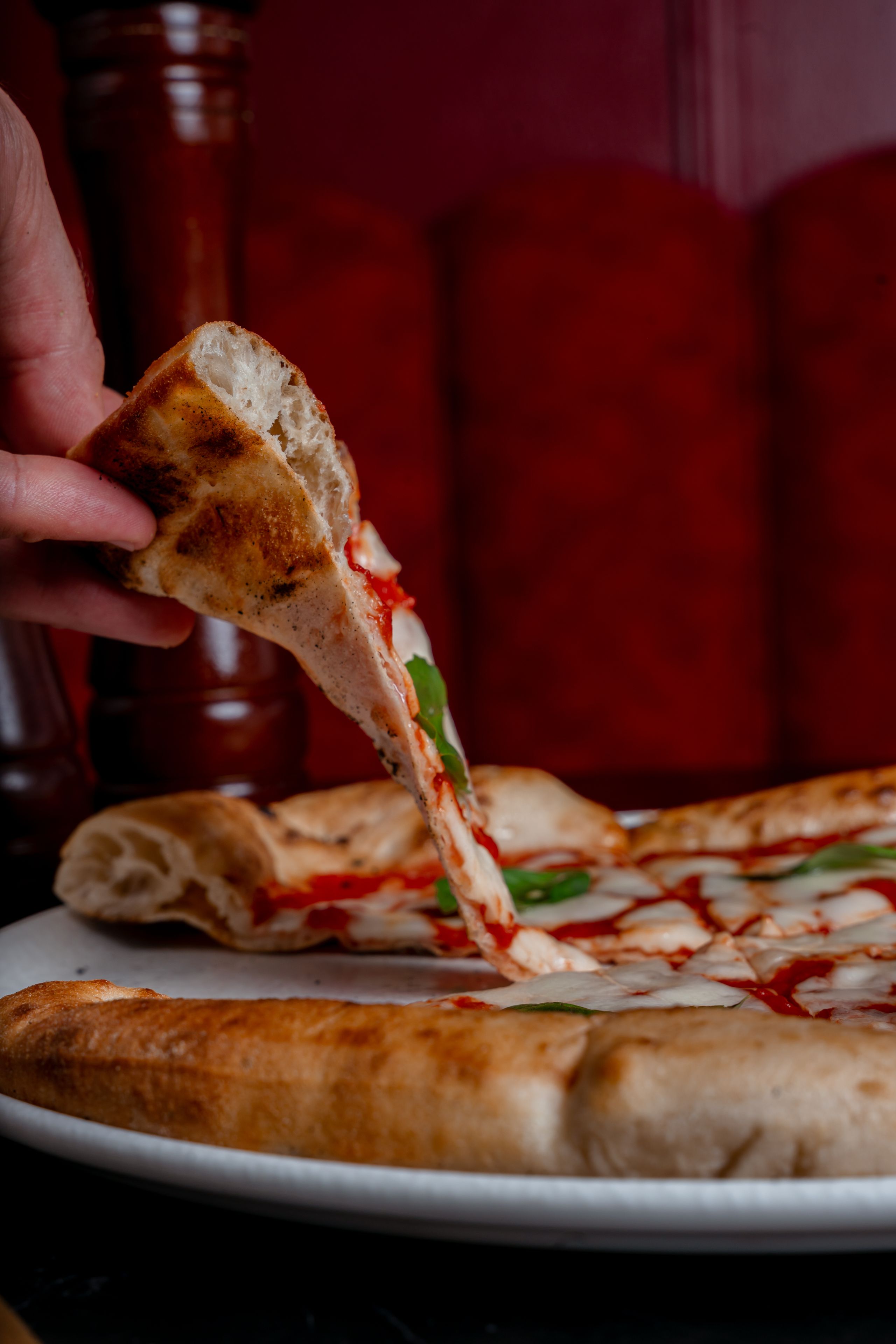 Fatia de pizza sendo puxada, com queijo derretido escorrendo