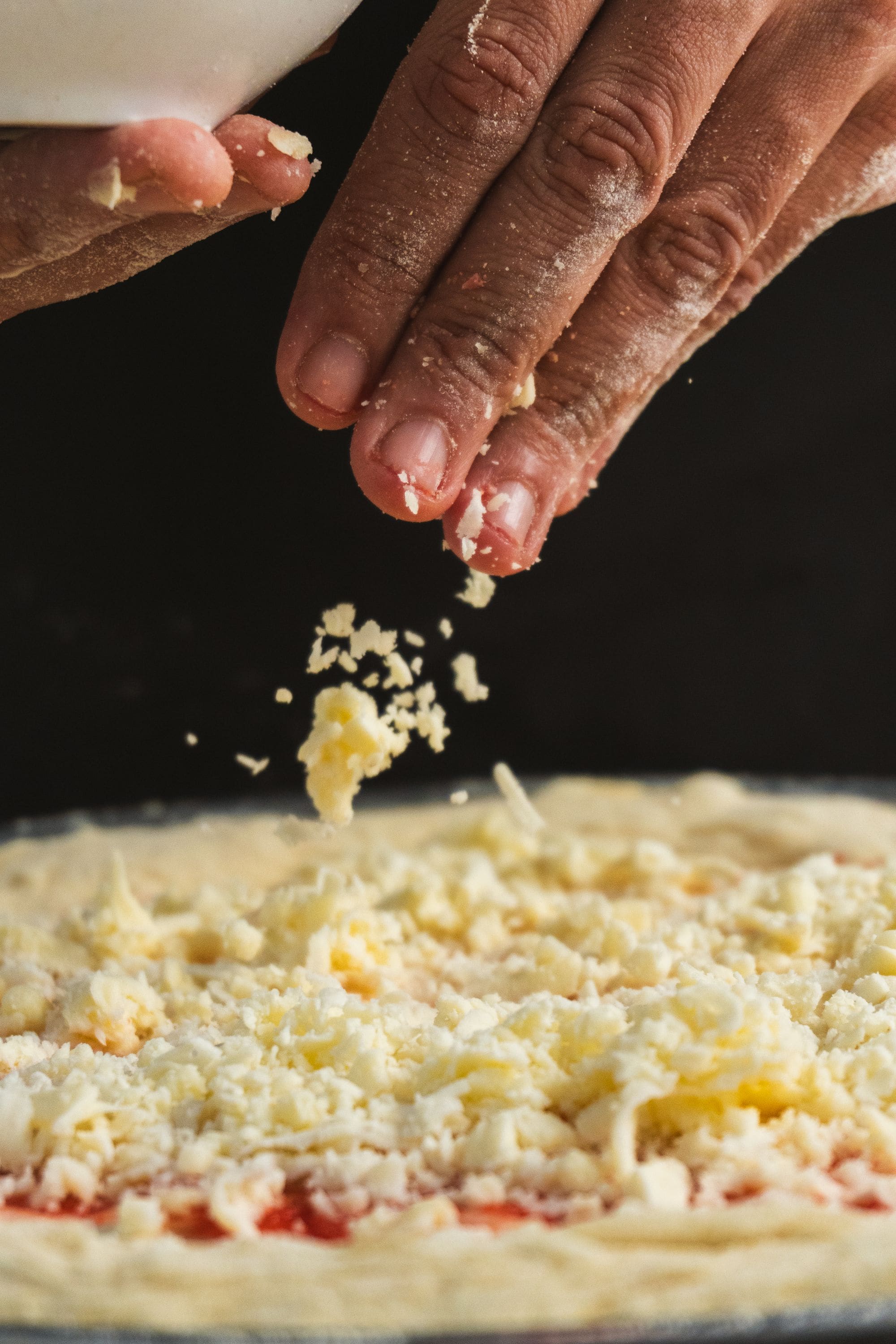 Mãos cobrindo a massa fresca com queijo